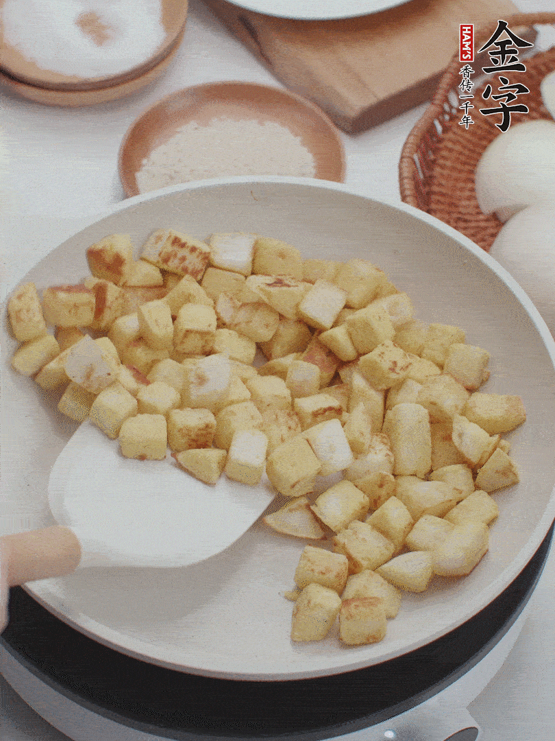 起鍋熱油，倒入饅頭丁，小火煎至蛋液凝固定型再翻面，饅頭丁部煎至金黃時(shí)盛起待用。